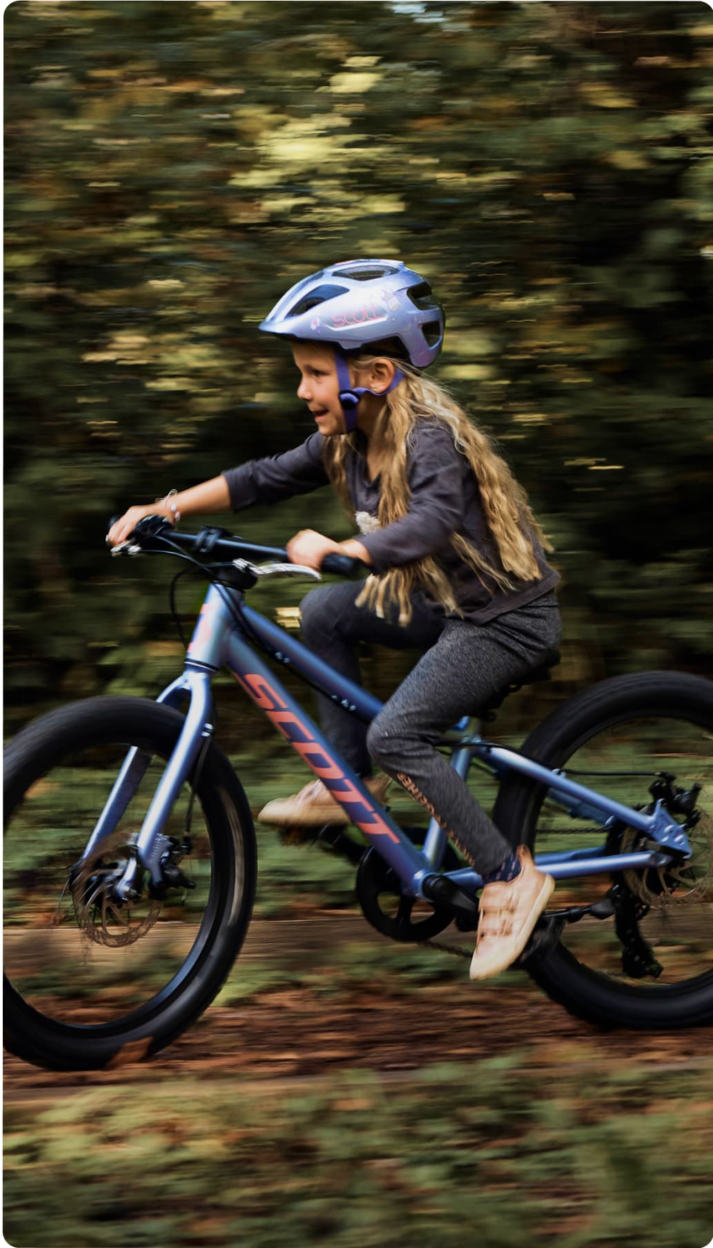 Young girl rides a blue bike through a forest.