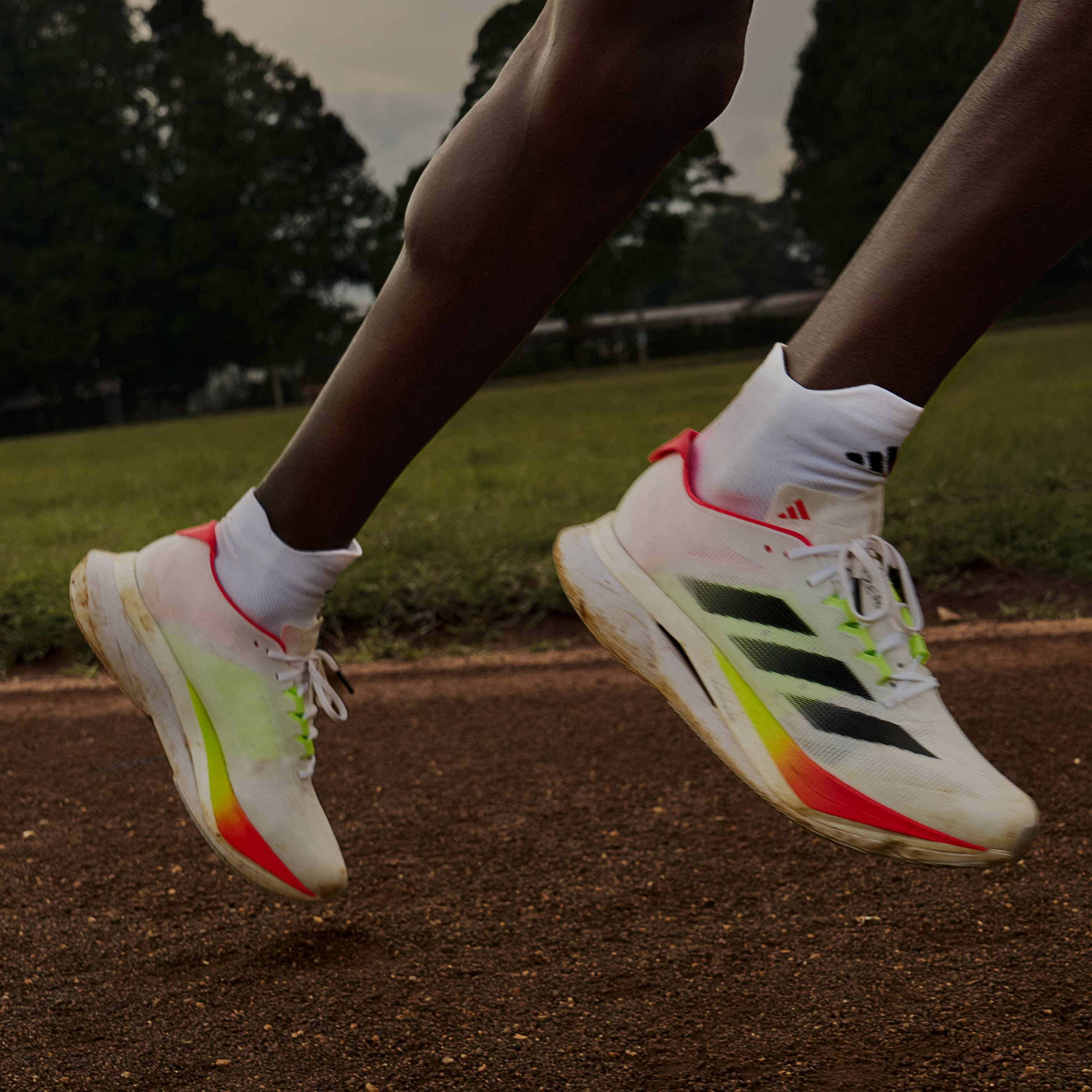 Close-up of a runner's legs on a track, wearing white running shoes.